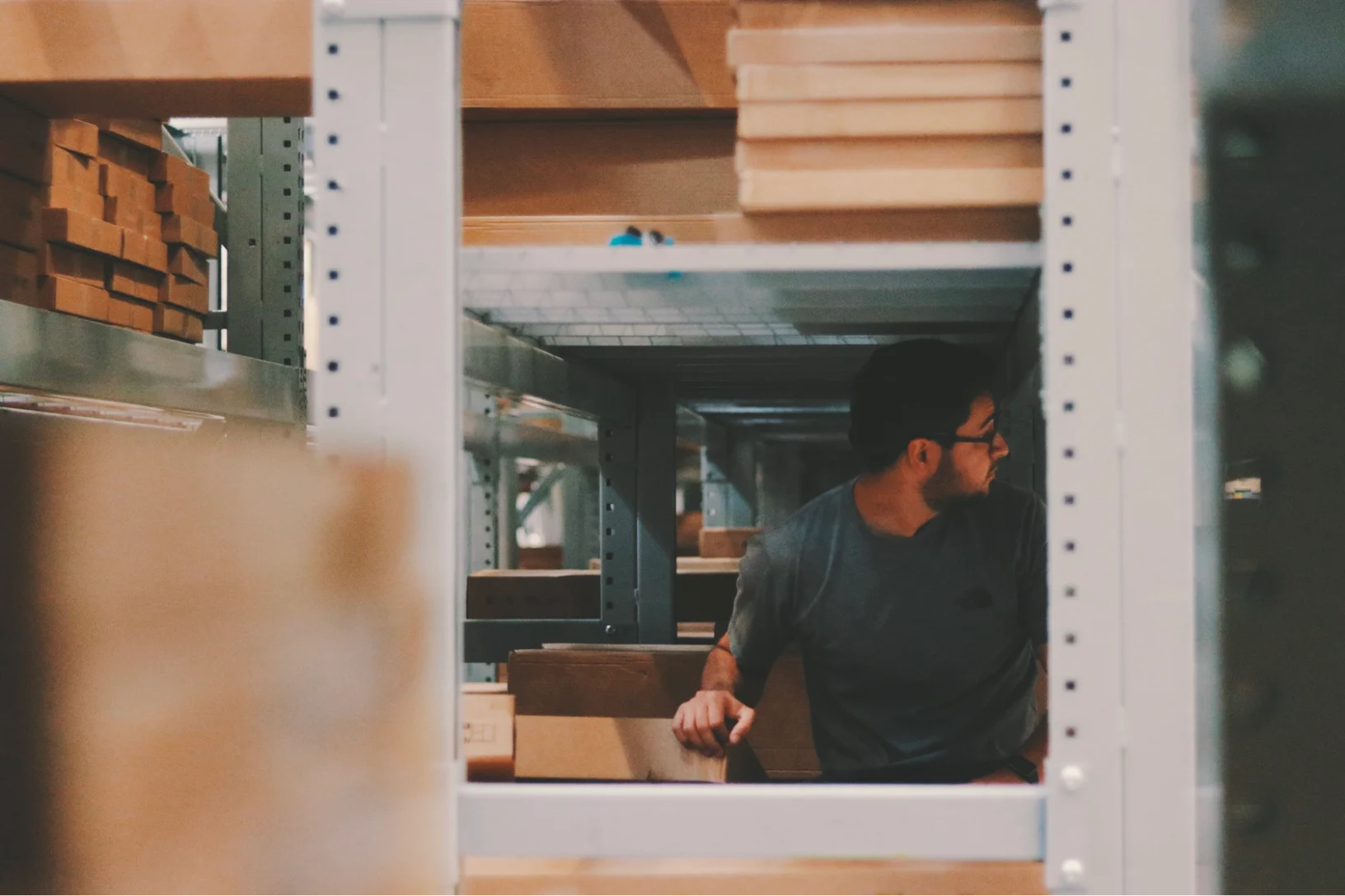 Warehouse worker surrounded by shelving units preparing shipments that trigger EDI 856 advance ship notice documents
