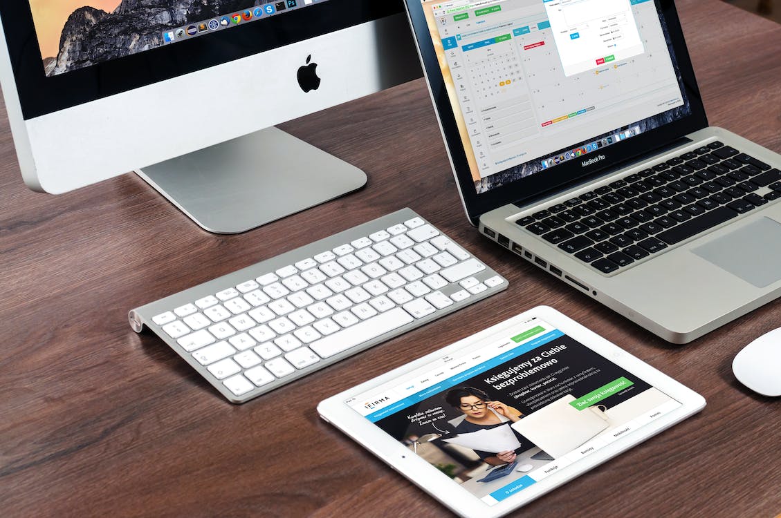 A laptop, tablet and computer together on a desk