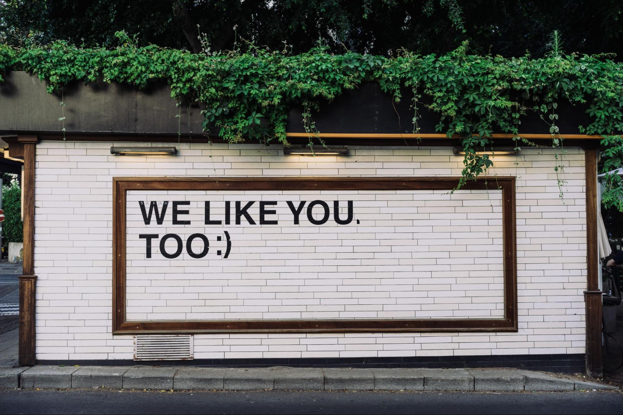 Graffiti on a wall saying "We like you too :)"