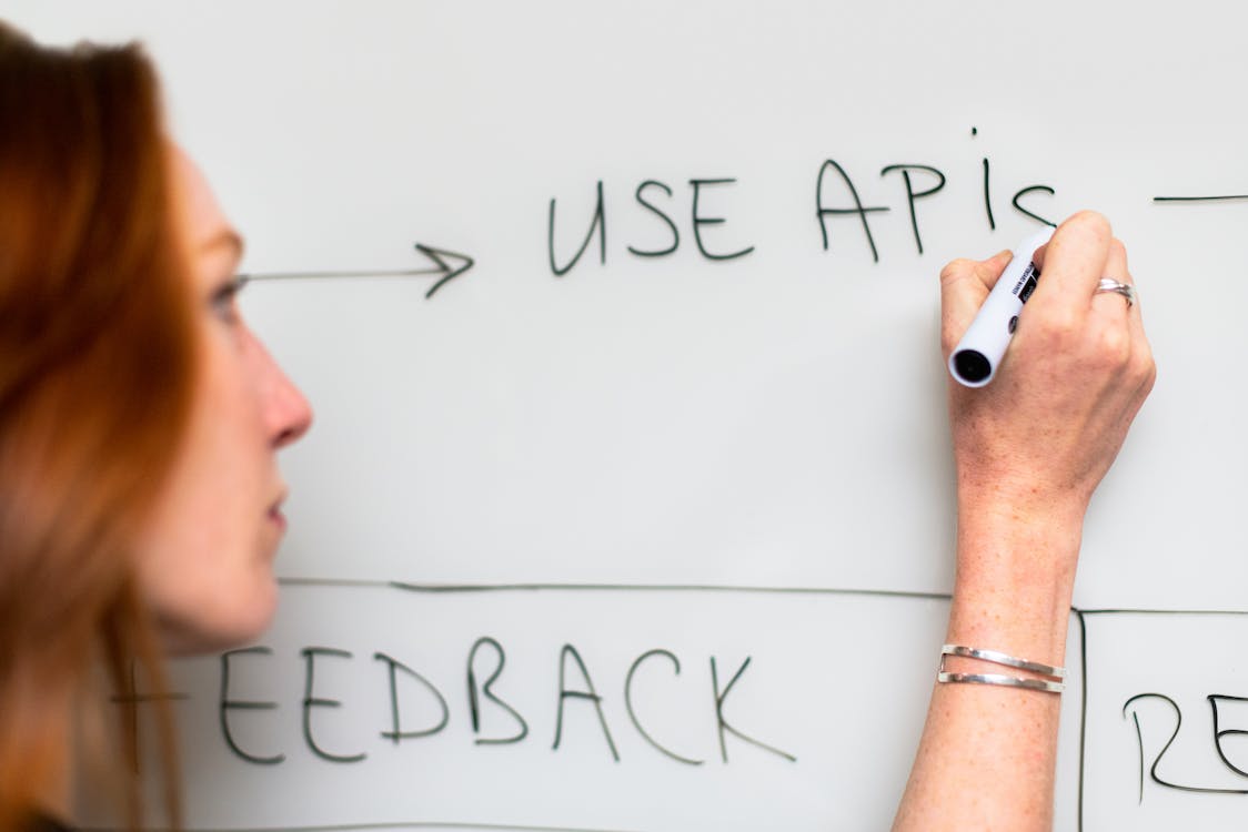 Woman writing "Use APIs" on whiteboard