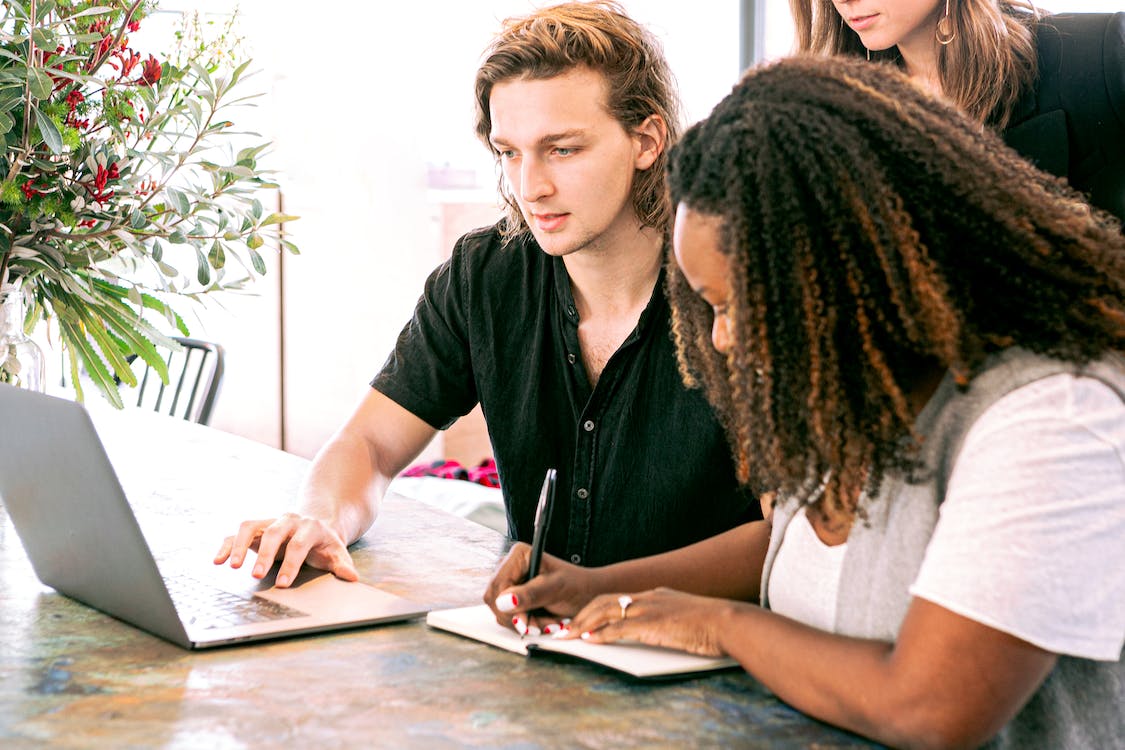 Three people working together with laptop and notebook.