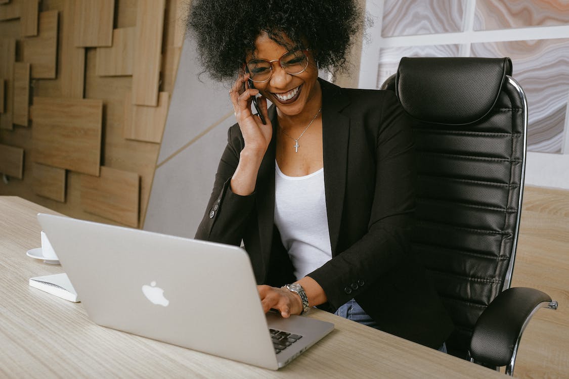 Woman talking on phone whilst working on laptop