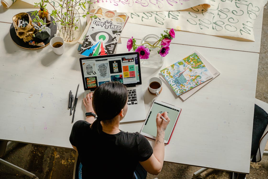 Person working at desk with tablet and laptop