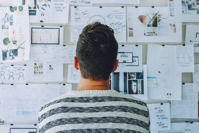 Man looking at wall with work documents pinned to it