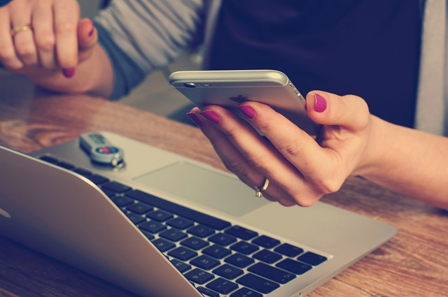 Person looking at smartphone and laptop simultaneously