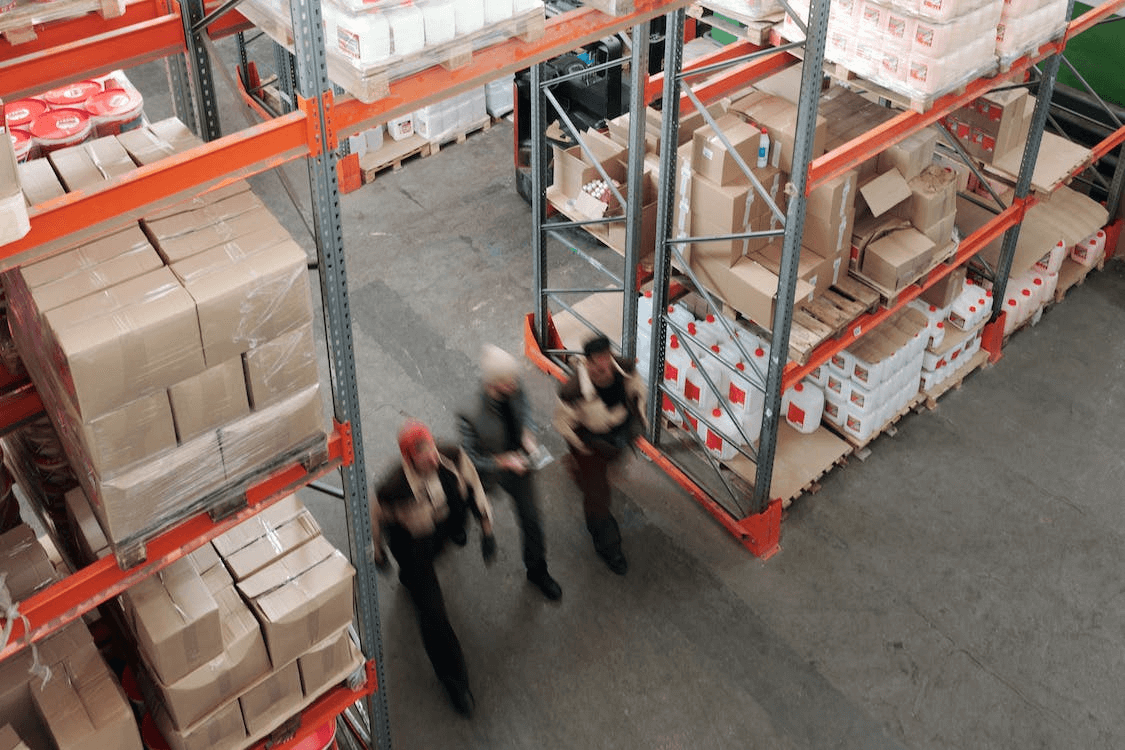 Three people walking through a warehouse.