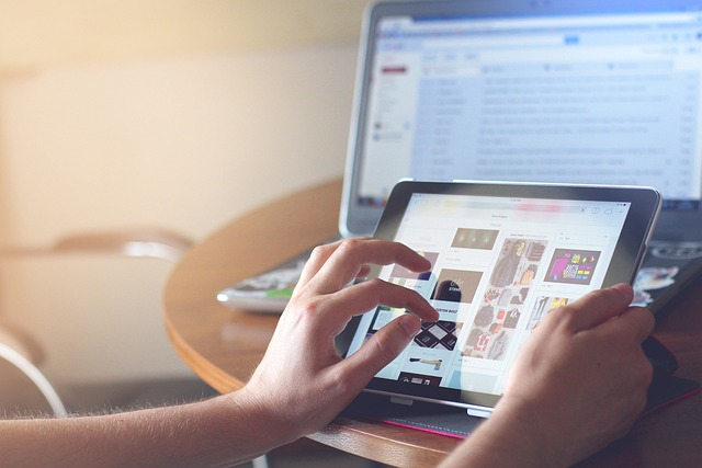 Person working on tablet with laptop in background