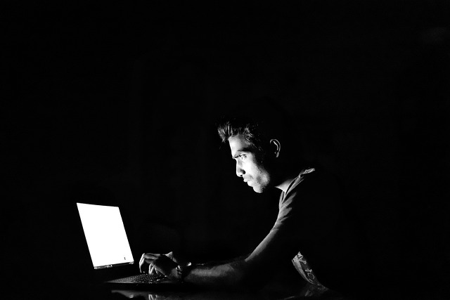 Black and white image of person working on laptop