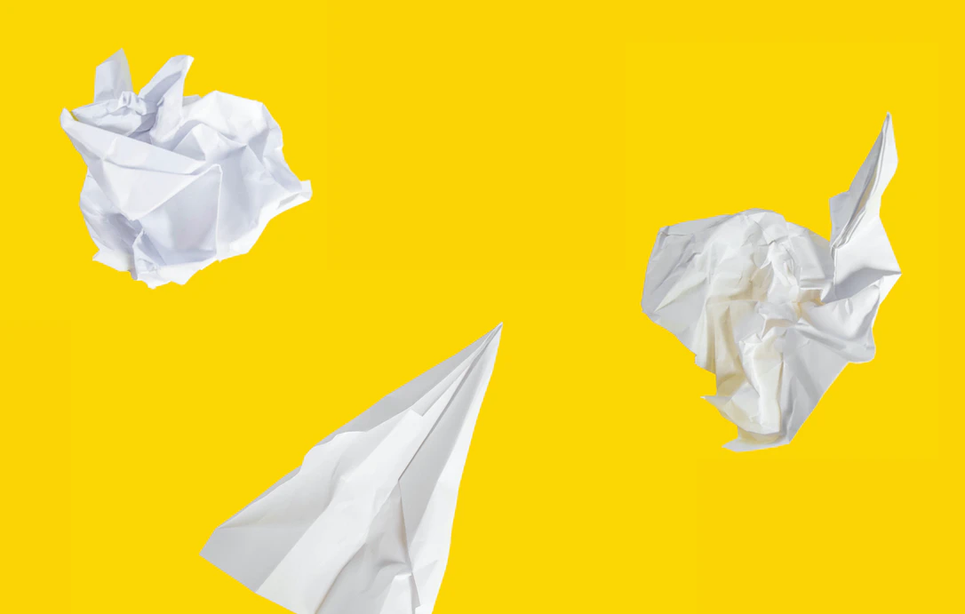 crumpled pieces of paper on a bright yellow background